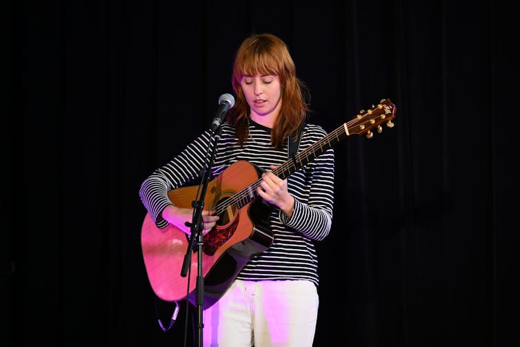 A woman plays guitar.