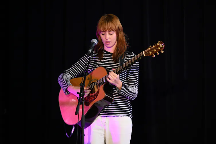 A woman plays guitar.
