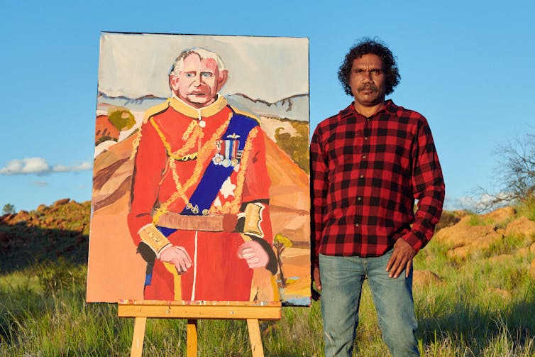 A man stands next to a painting of King Charles.
