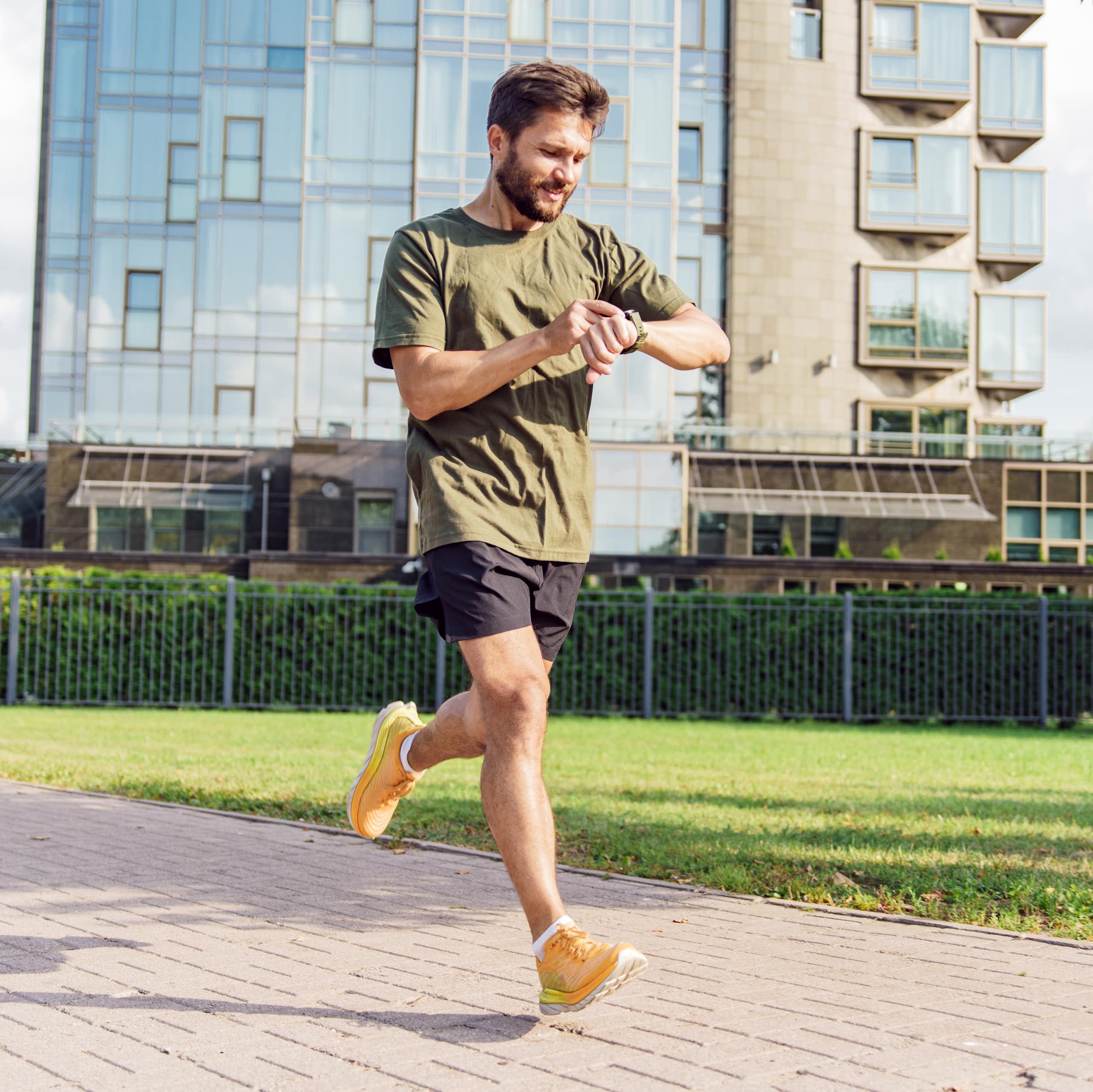 A man checks his smart watch while out on a run.