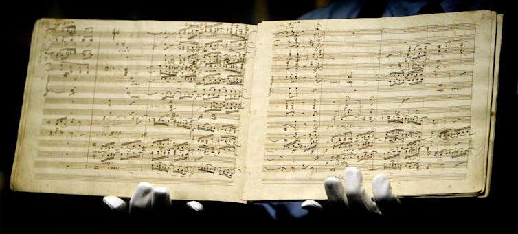 An open book shows pages full of musical notes.