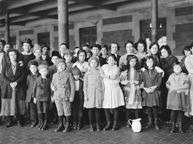 Three rows of children and young adults stand formally as they pose in a courtyard.