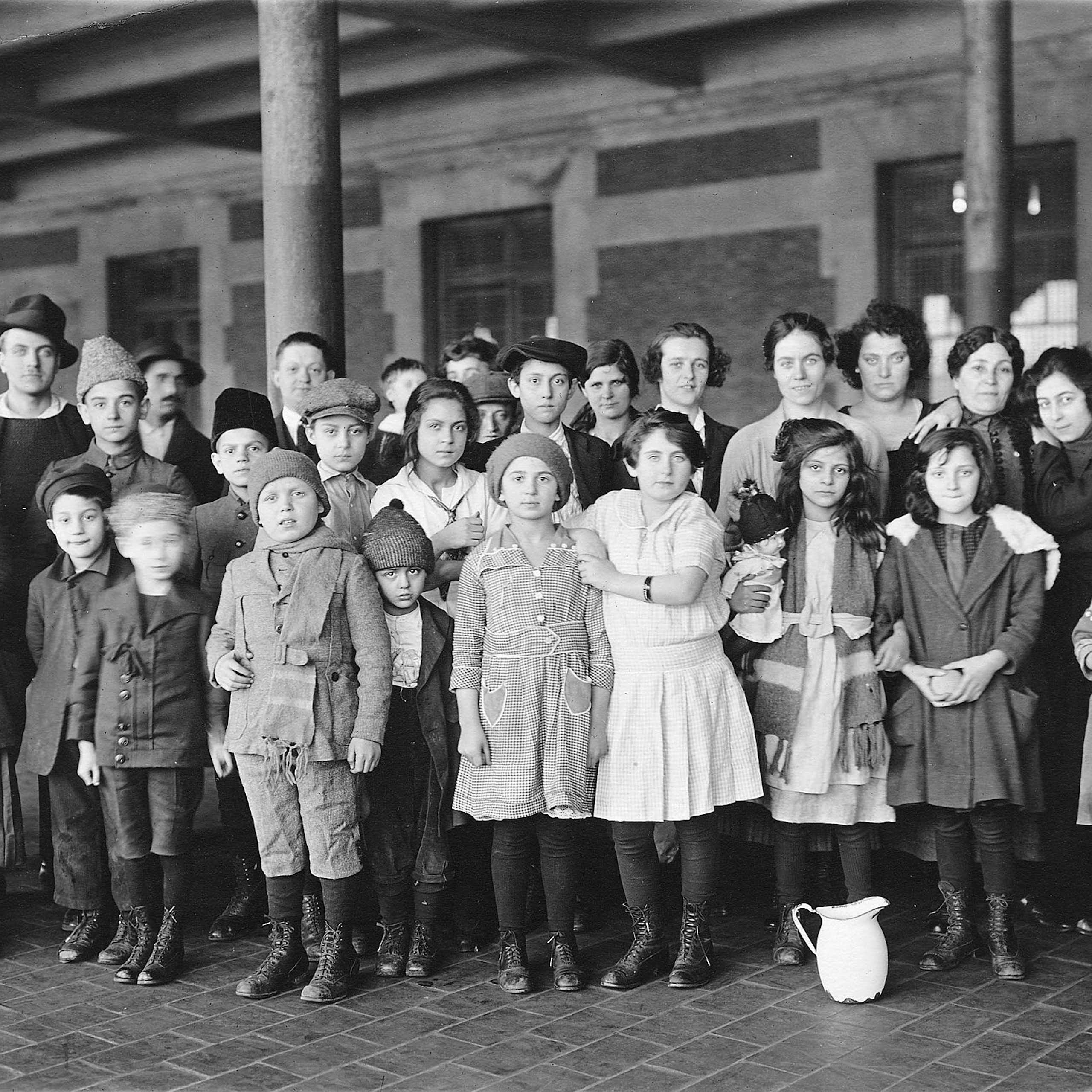Three rows of children and young adults stand formally as they pose in a courtyard.