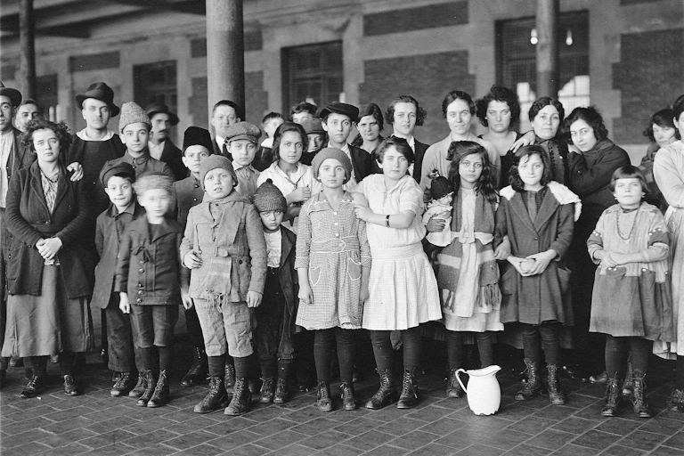 Three rows of children and young adults stand formally as they pose in a courtyard.