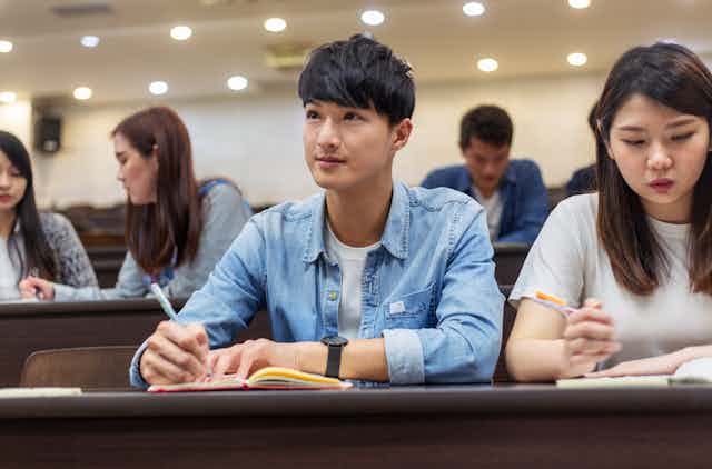 College students take notes in a lecture hall.