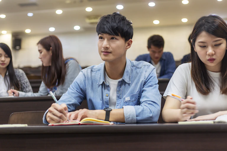College students take notes in a lecture hall.