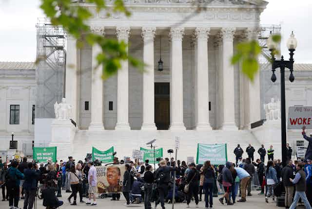 People protesting in front of a large white building with tall columns.