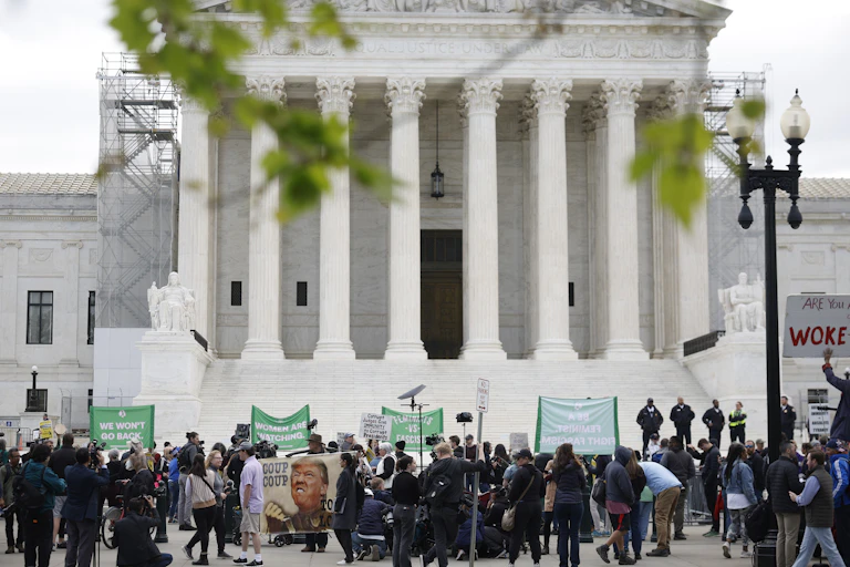 People protesting in front of a large white building with tall columns.
