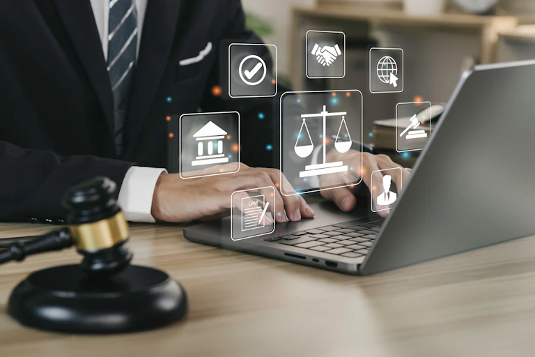 A person in a suit typing on a laptop, with images of legal scales and other justice related icons emitting from the screen