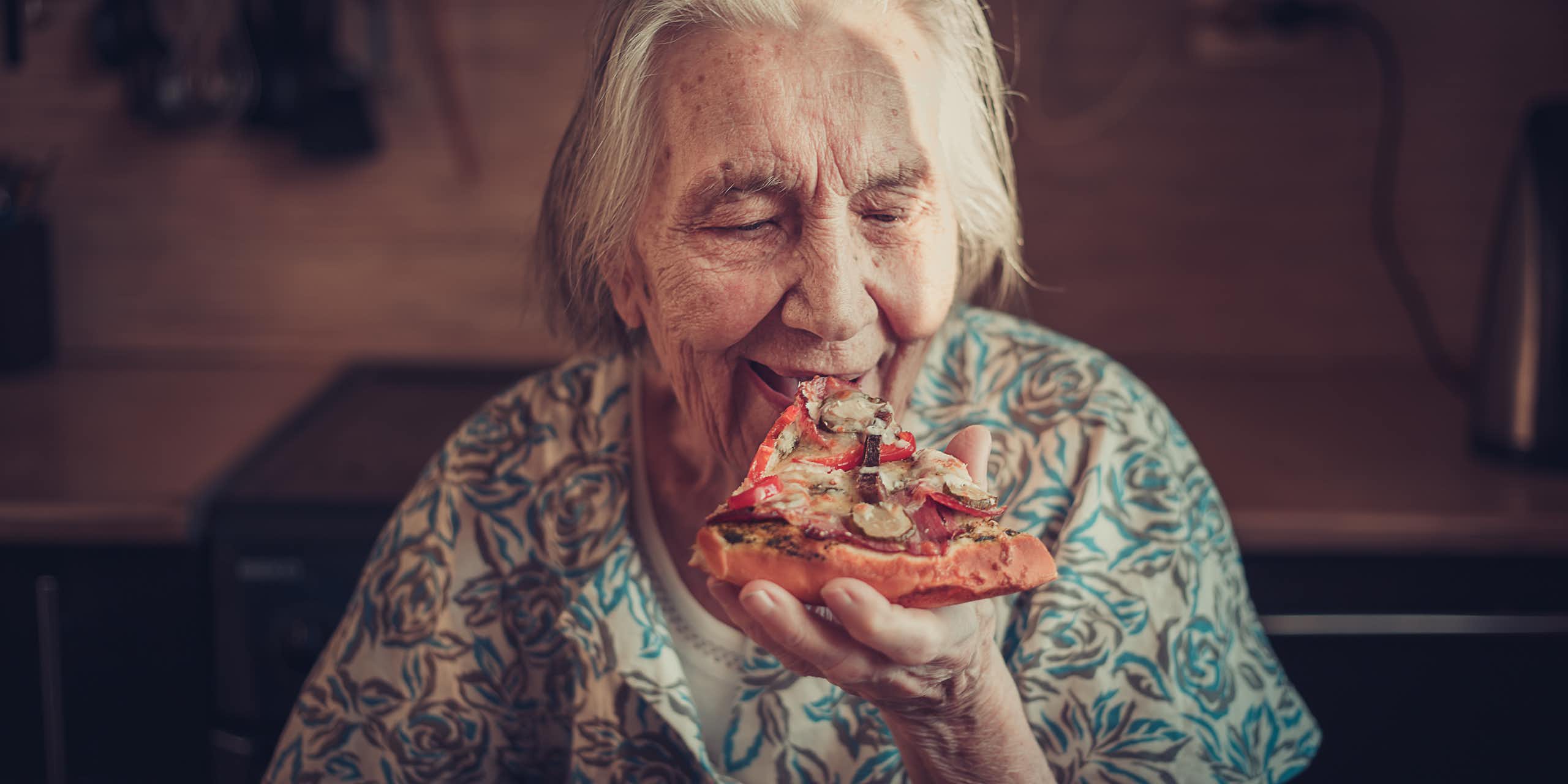 Une femme âgée mangeant une part de pizza