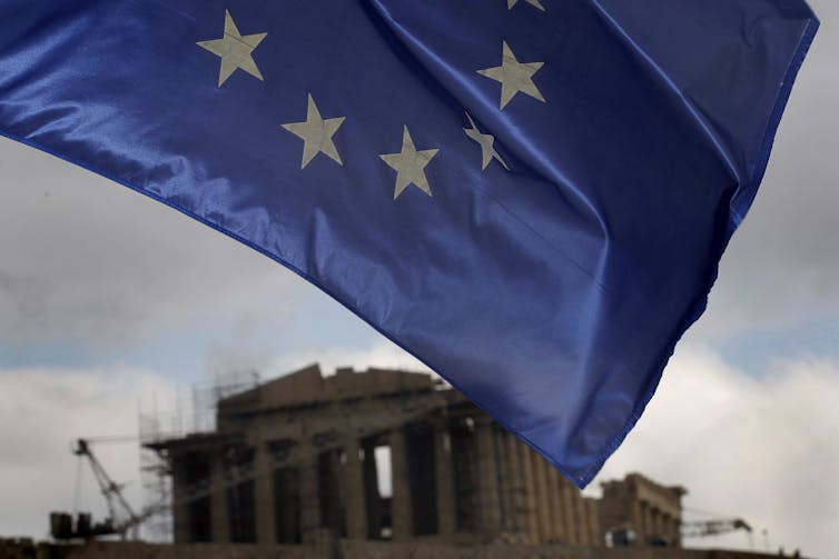 European Union flag seen flying with the Acropolis of Athens in background