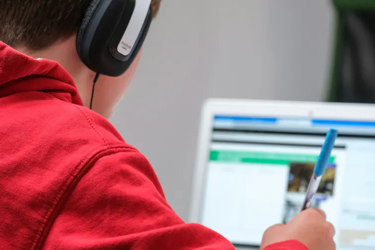 boy sits at laptop wearing headphones