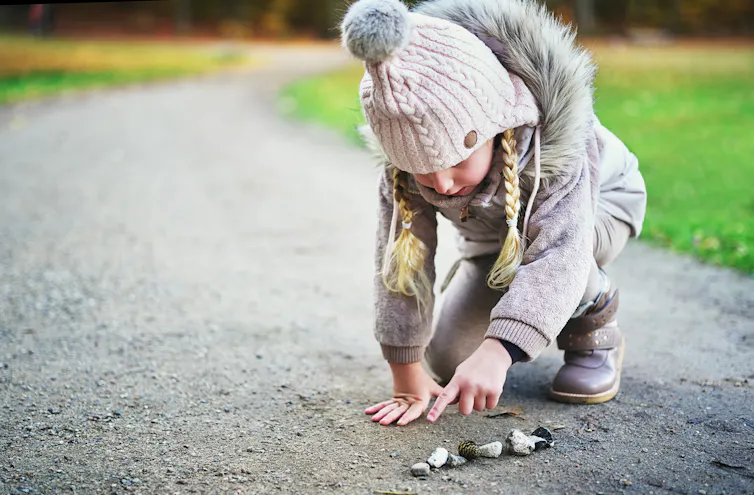 Girl points on stones outside.