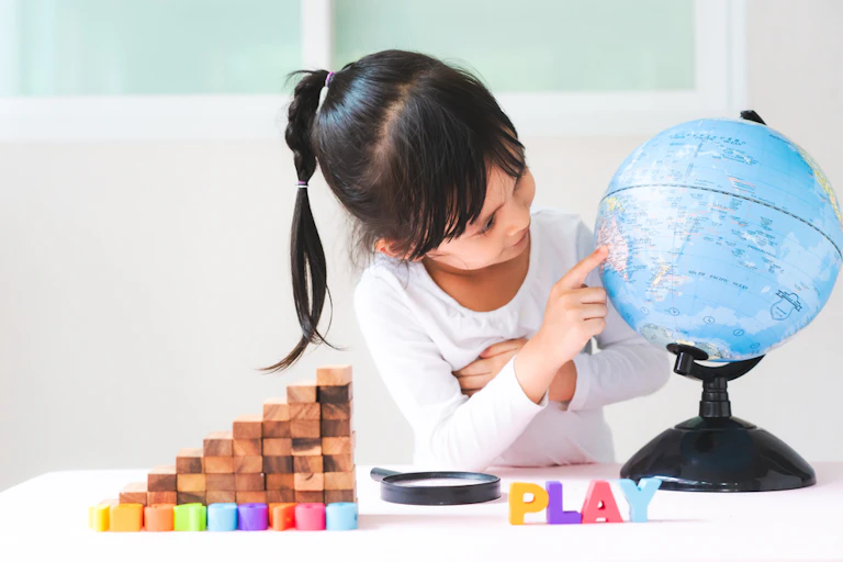 Une petite fille qui joue avec des cubes et un globe