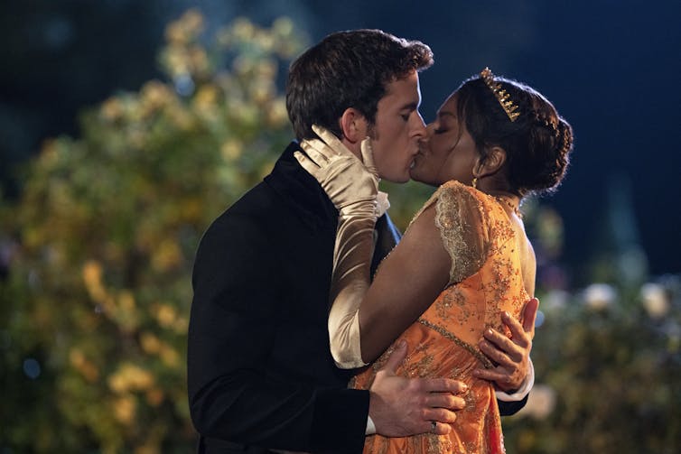 Jonathan Bailey as Anthony Bridgerton, Simone Ashley as Kate Sharma kissing in a garden.