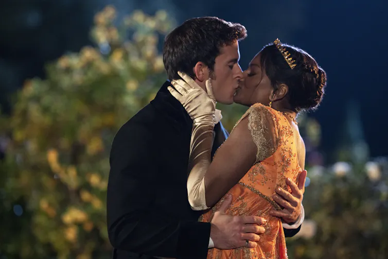 Jonathan Bailey as Anthony Bridgerton, Simone Ashley as Kate Sharma kissing in a garden.