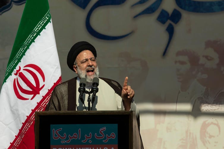 Ebrahim Raisi gives a speech in front of an Iranian flag.