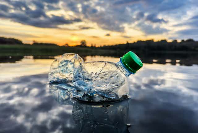 A scrunched up plastic bottle floats on a body of water.