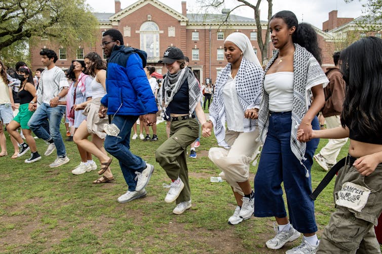 People hold hands in a line and dance.