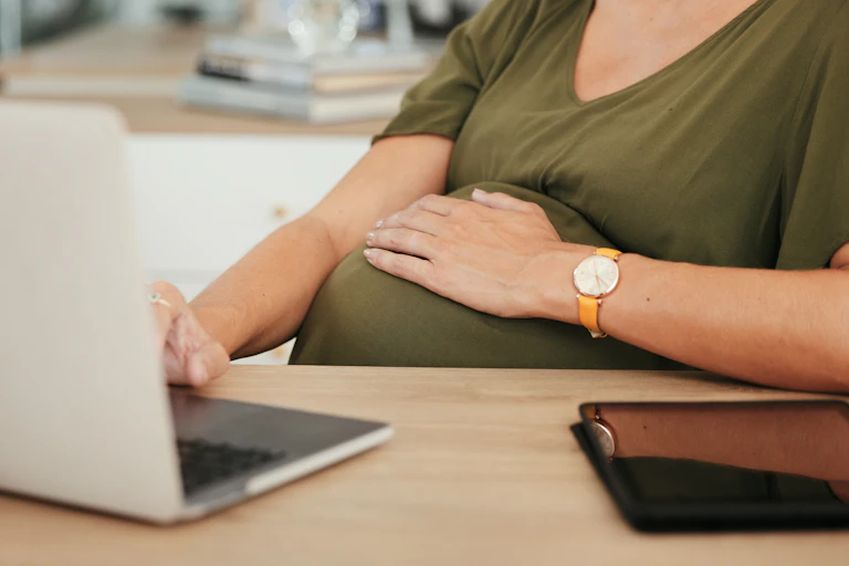 Une femme enceinte travaille sur un ordinateur.