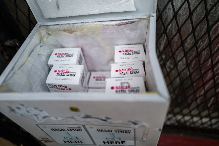 A white box contains boxes of Narcan nasal spray with 