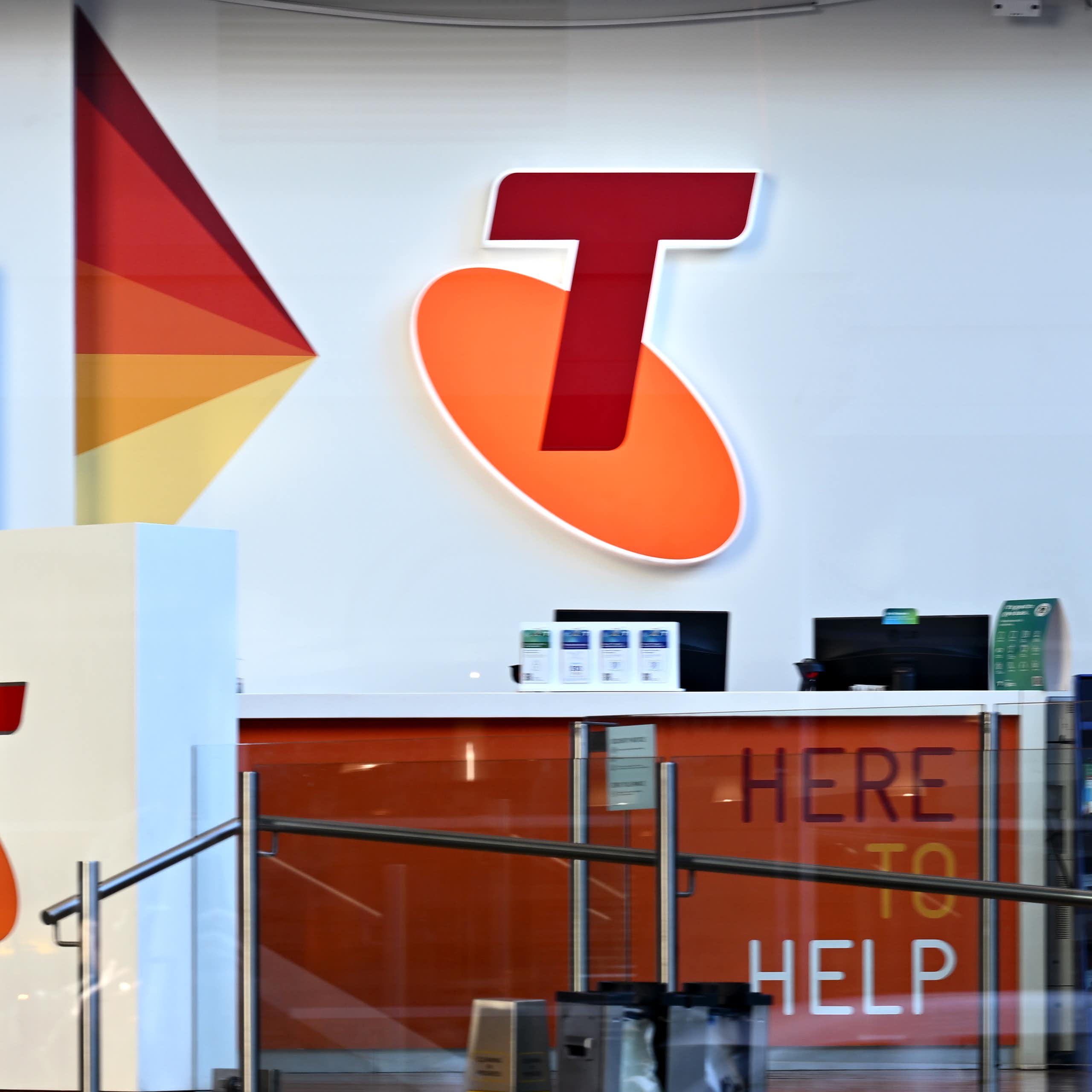 Blurred man seen walking in front of a large Telstra shop