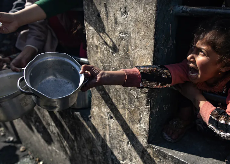 Uma criança palestina esperando por ajuda alimentar.