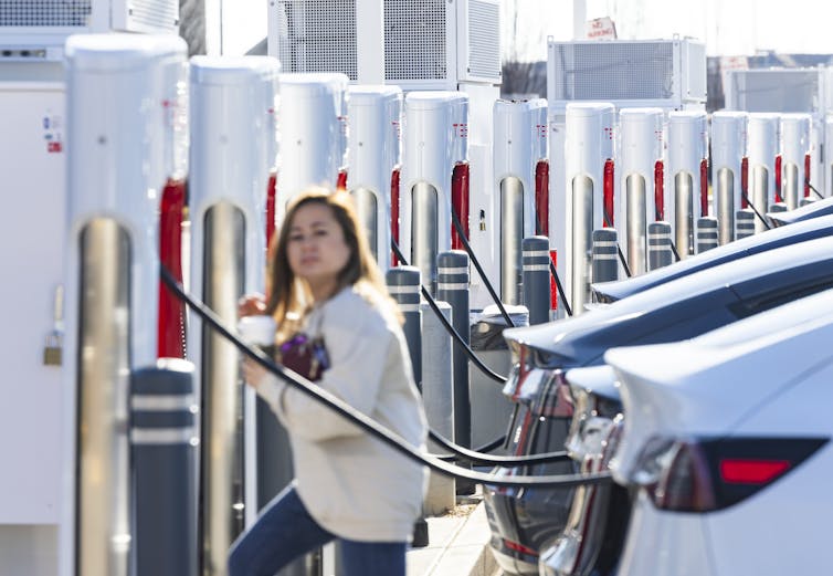 Woman charging a car at a Tesla supercharging station
