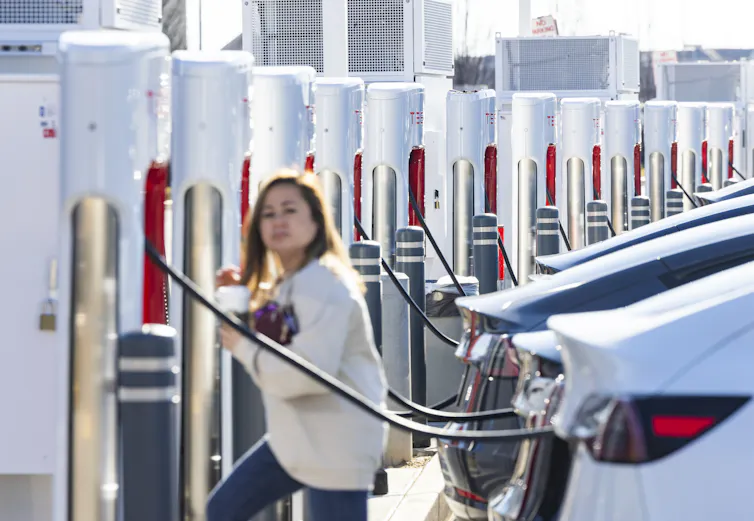 Woman charging a car at a Tesla supercharging station