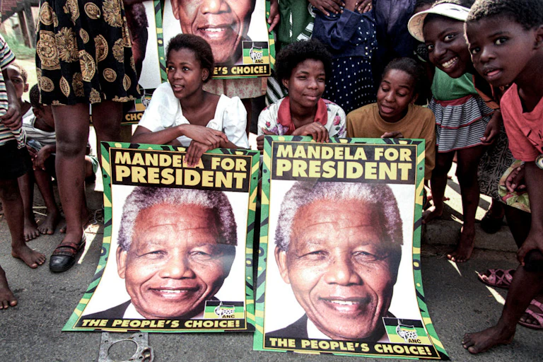 Young people pose with posters saying 'Mandela for president'.