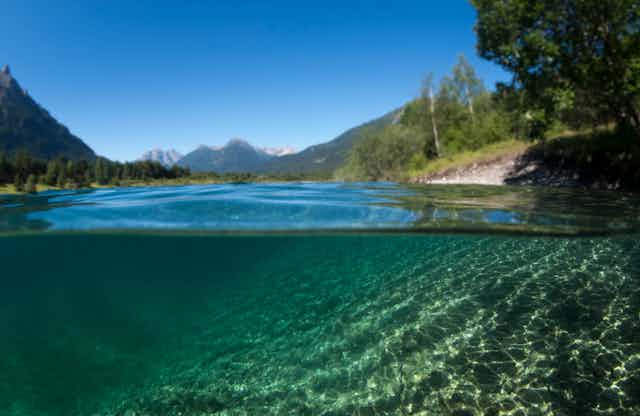 a lake underwater with shores and mountains in the background