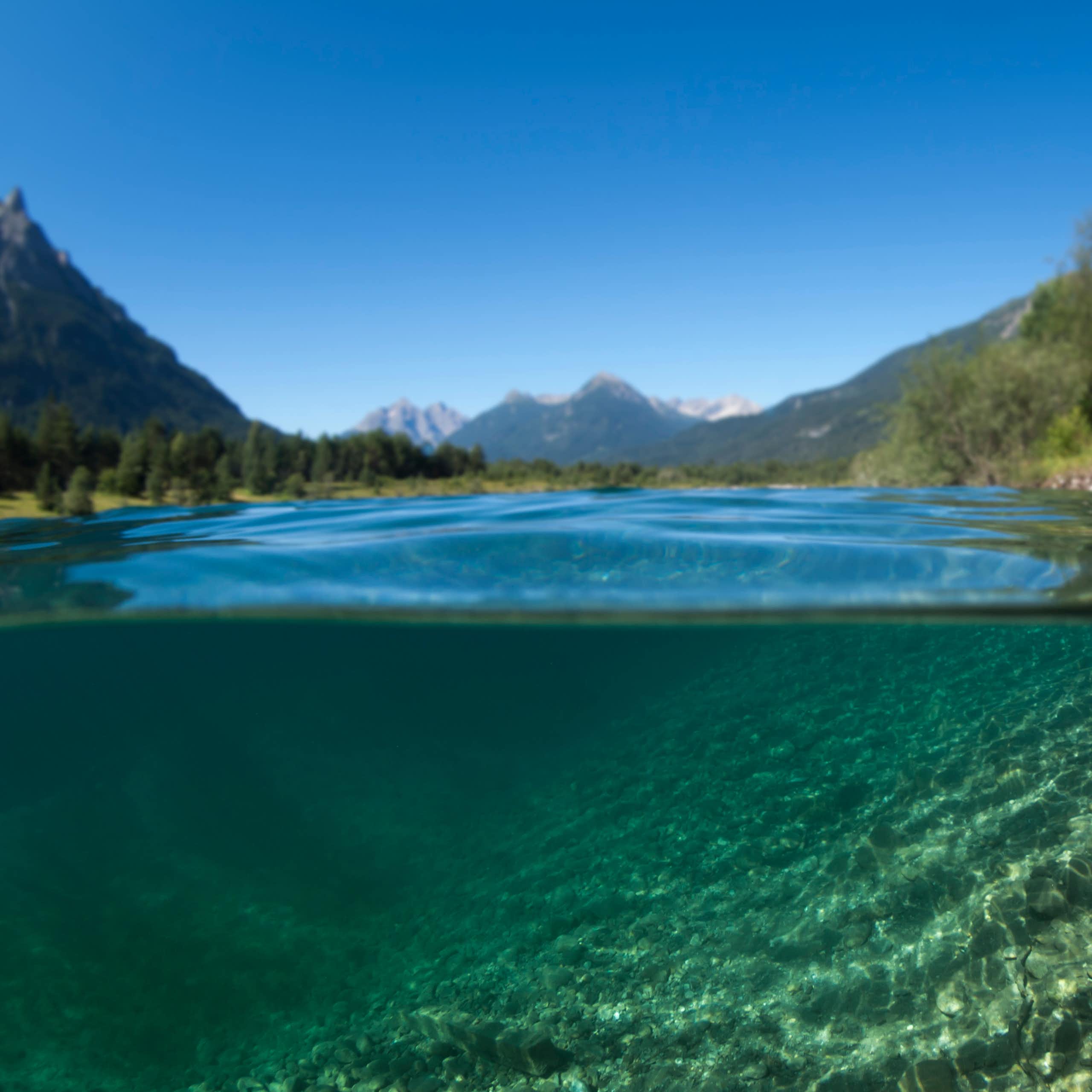 a lake underwater with shores and mountains in the background
