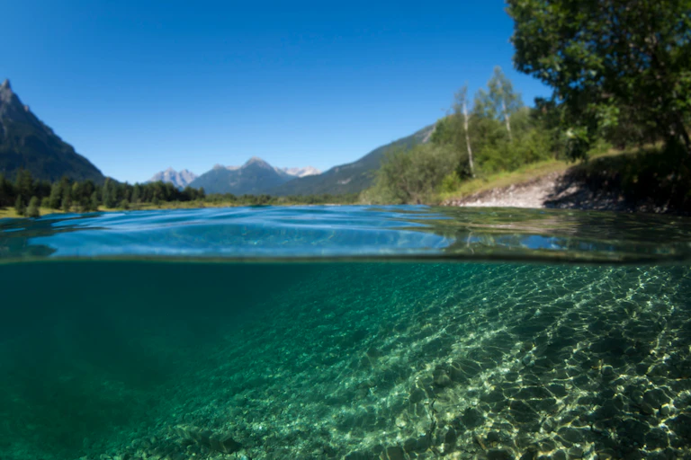 a lake underwater with shores and mountains in the background