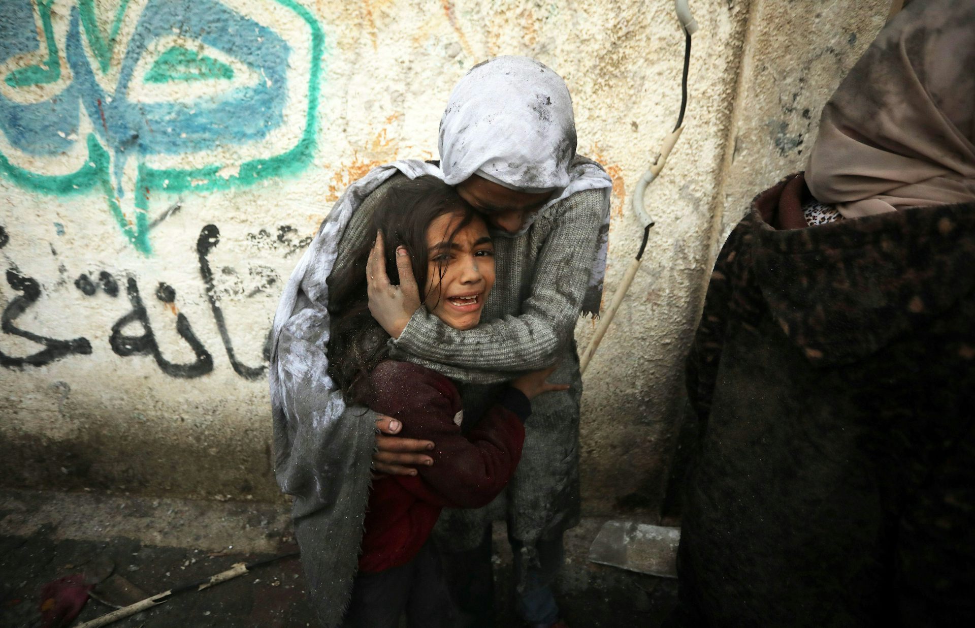 A mother cradling the head of her crying child.