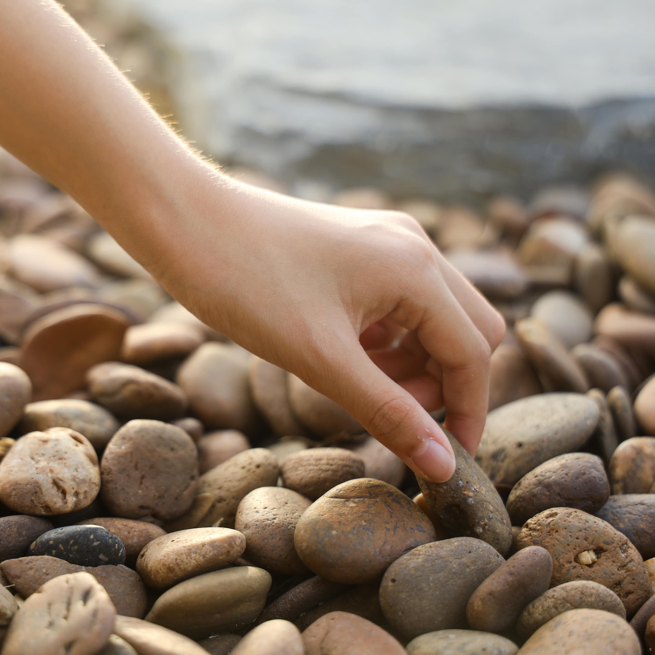 Hand picking up pebble on a beach