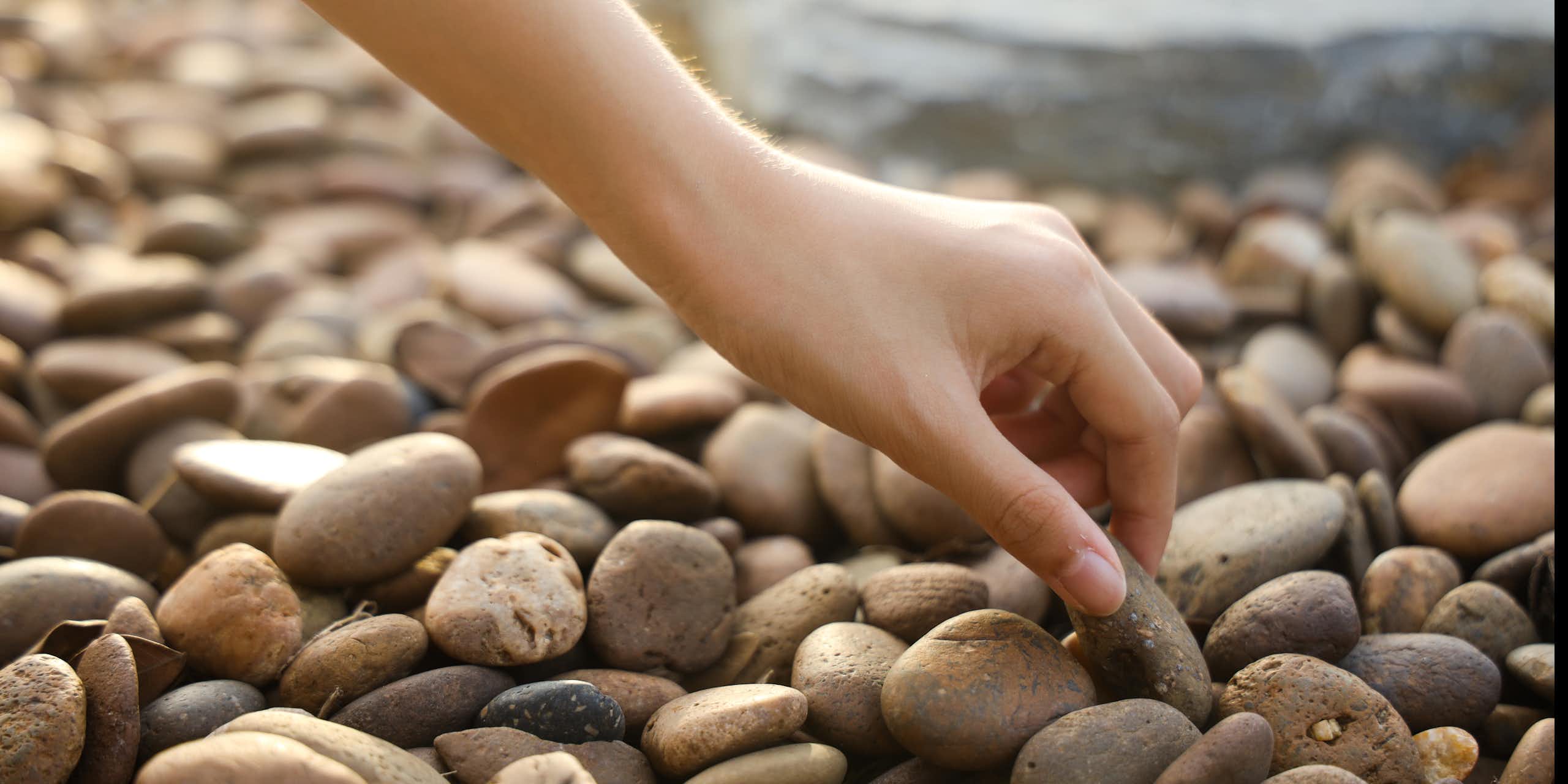 Hand picking up pebble on a beach