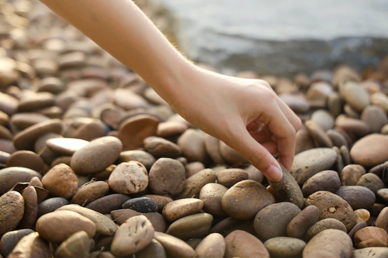 Hand picking up pebble on a beach