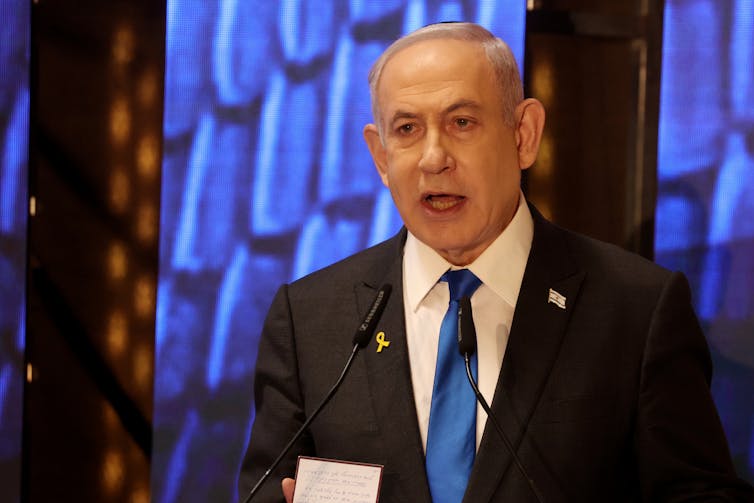 Benjamin Netanyahu dressed in a suit and delivering a speech.