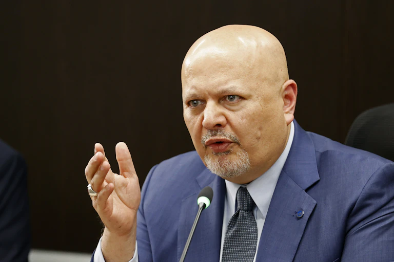 A bald man with a goatee beard speaking into a microphone.