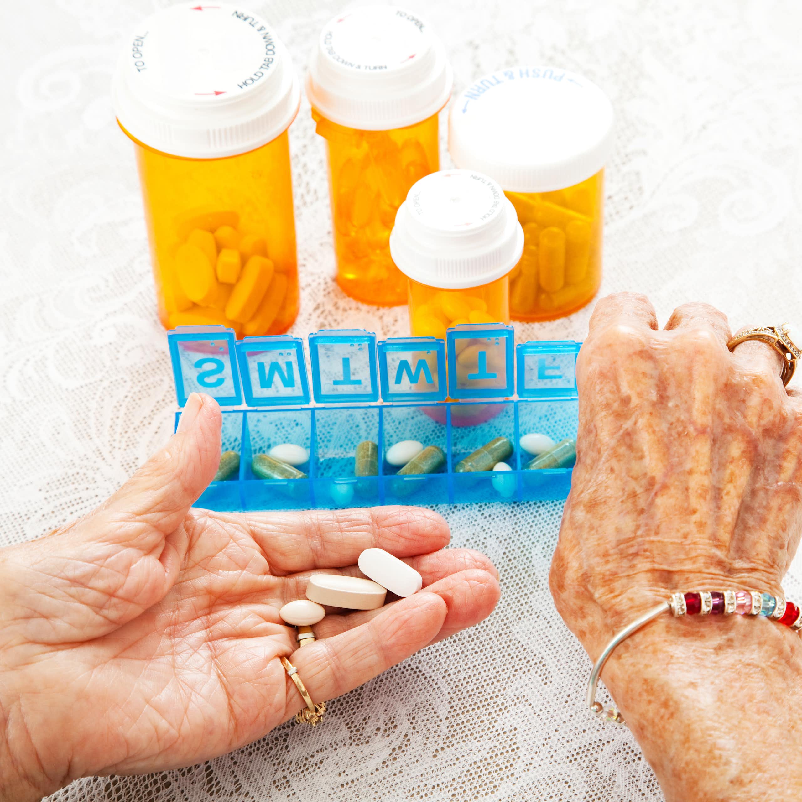 The hands of an elderly person taking medication in a box