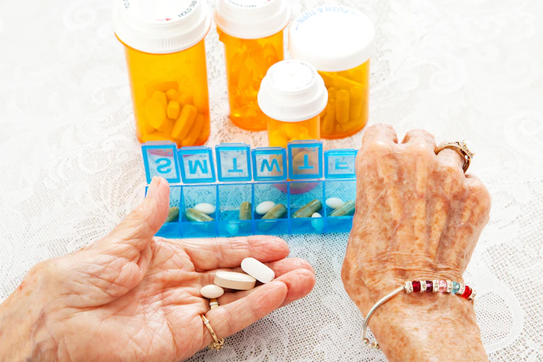 The hands of an elderly person taking medication in a box