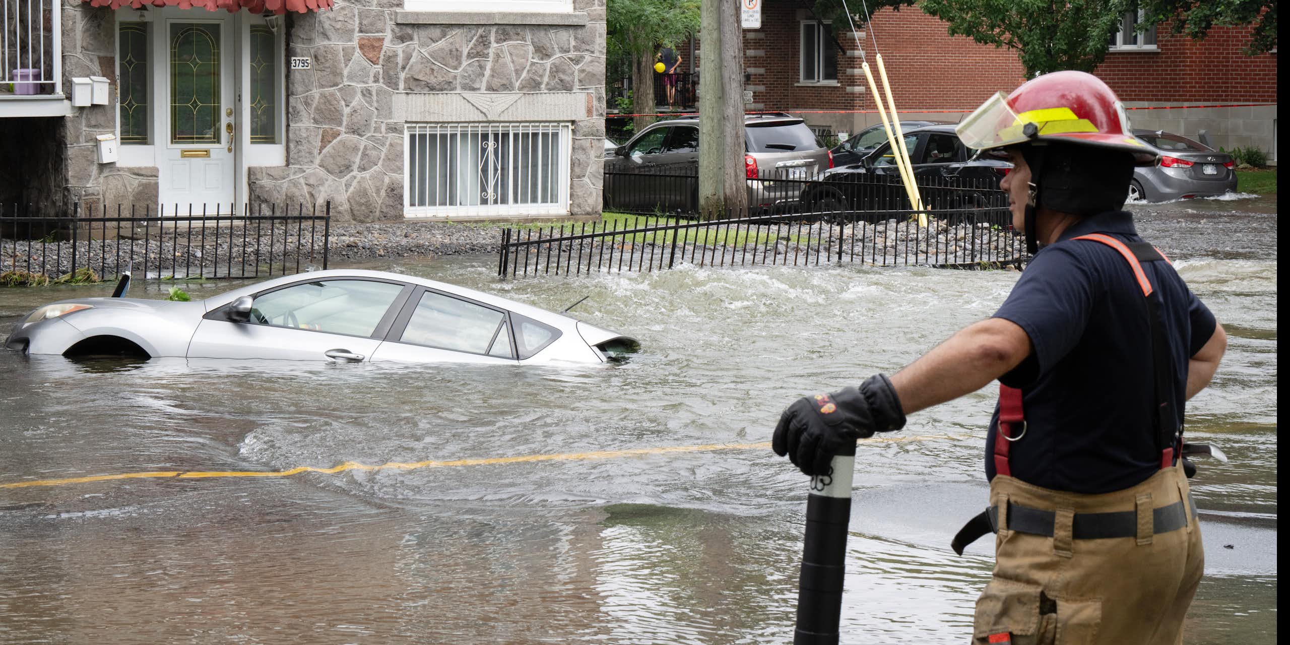 Un pompier se tient en marge d'une rue inondée