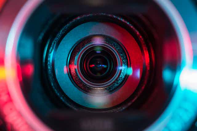 Close-up of video camera lens lit in red and blue