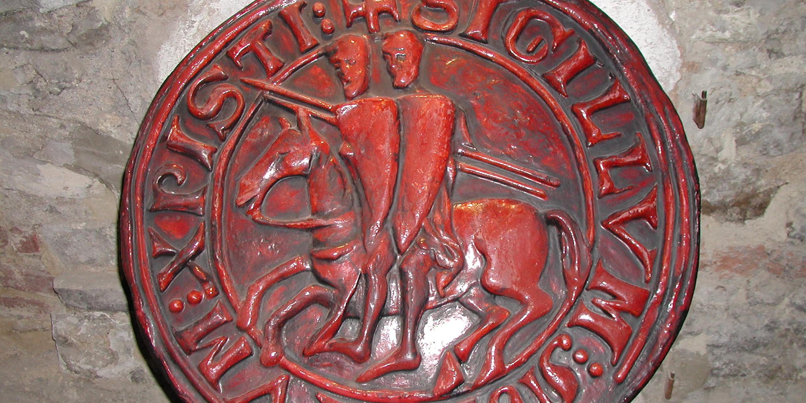 Circular, red seal depicting two knights sitting on one horse