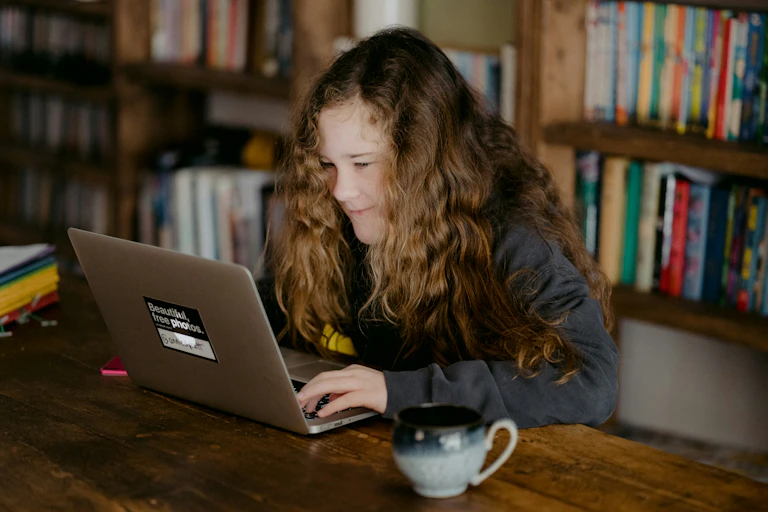 Girl does schoolwork at table.