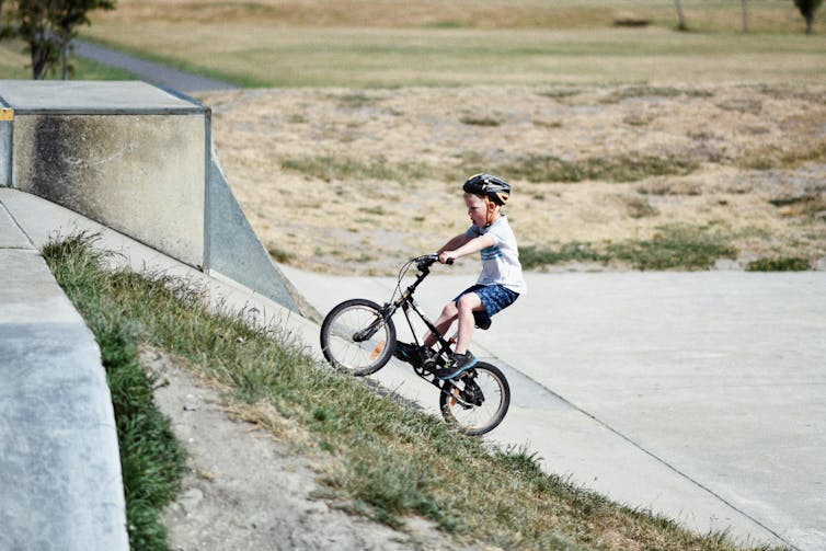 A child is riding a bike on a ramp.