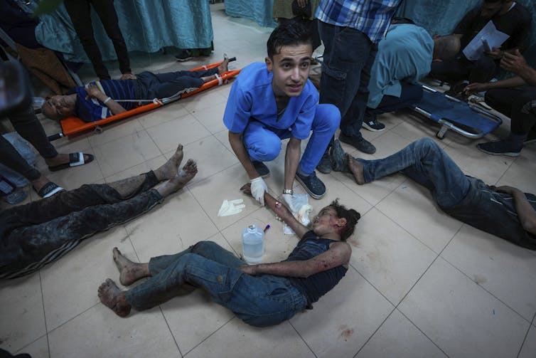 A doctor with a wounded boy lying on the floor.