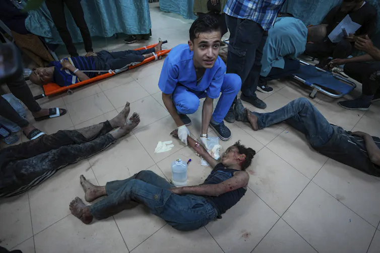 A doctor with a wounded boy lying on the floor.