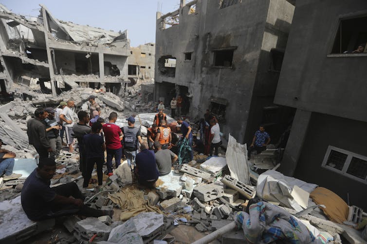 Palestinians search through the wreckage of a bombed building.