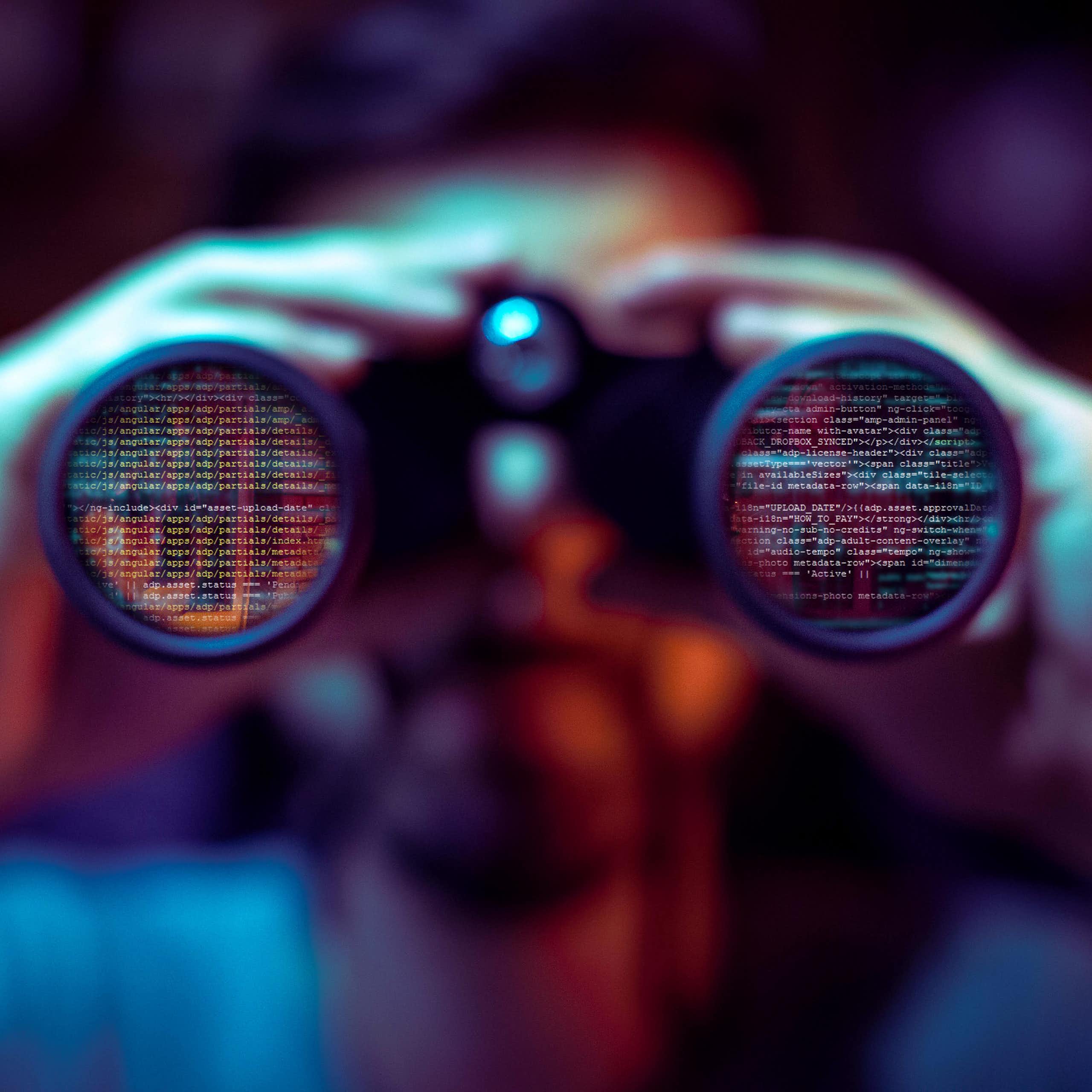 Man looking through binoculars at data